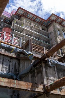 Historisches Gebäude unter Sanierung, über einer tiefen städtischen Baugrube mit massiver Metallverbauung und Betonwänden.