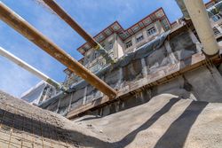 Tiefansicht einer Baustelle mit großen Rohren, Ausschachtung und einem historischen Gebäude unter blauem Himmel.